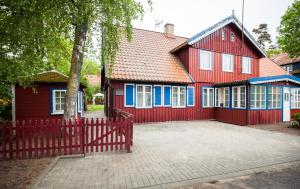 a red house with a red fence and a tree at Skruzdynes 11 in Nida