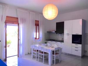 a white kitchen with a white table and a white cabinet at Appartamento Aria 150m dal mare in Castelsardo