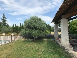 um quintal com uma cerca e uma árvore ao lado de uma casa em Bastide CAMPAGNE CANAL em Cucuron