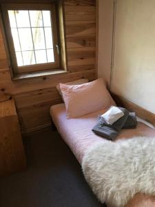 Dormitorio pequeño con cama con almohada y ventana en Appartement Duplex avec Jardin Attenant, en Briançon