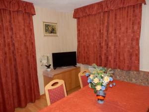 a room with a table with red curtains and a television at La Pineta in Colfosco