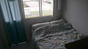 un letto non rifatto in una stanza con finestra di ILHA DOS CORAIS -Ap 304 C a Balneário Praia do Leste