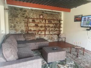 a living room with a couch and a stone wall at Naisar's Apartments Primrose,Johannesburg in Johannesburg