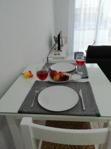 a table with two white plates and glasses of red wine at Ocean Blue Apartments in Paphos City