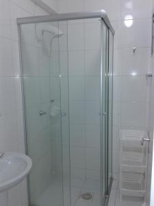 una ducha con una puerta de cristal junto a un lavabo en Apto bem localizado, en Balneário Camboriú