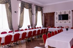una sala de conferencias con mesas blancas y sillas rojas en Pałac Brody, en Brody