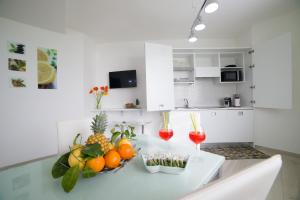 a white kitchen with a table with fruit and drinks at Villa Bellatrix in Massa Lubrense