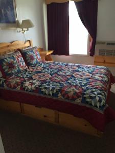 Una cama con edredón en un dormitorio en Valley Hotel & 24/7 Open Cafe, en Palmer