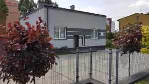 Biały dom za płotem w obiekcie Apartament Angelo w mieście Sosnowiec
