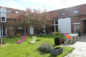 a yard with colorful chairs and a table in front of a building at L'Heure Bleue gîtes et chambres d'hôtes in Givenchy-en-Gohelle