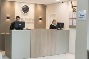 two people sitting at a counter with their computers at Hotel Trevo Cascavel in Cascavel