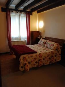 1 dormitorio con 1 cama y una ventana con cortinas rojas en Agroturismo Iturbe, en Axpe de Busturia