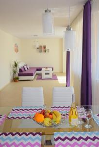 Rusalka Apart-Residence في ابزور: طاولة غرفة طعام مع فاكهة عليها ستائر أرجوانية