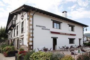 un edificio blanco con mesas y sillas delante en CASA RURAL BARAZAR en San Sebastián