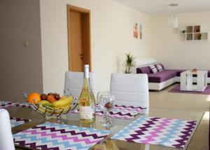 Rusalka Apart-Residence في ابزور: طاولة زجاجية مع وعاء من الفواكه وزجاجة من النبيذ