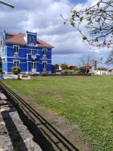 a blue house with a green field in front of it at La Clinica in Ballota