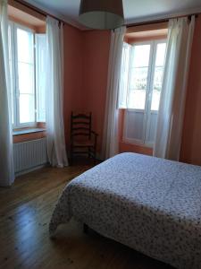 a bedroom with a bed and two windows and a chair at La Clinica in Ballota