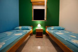 two beds in a room with a green wall at Apartmani HRGA in Vodice