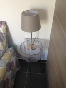a lamp on a glass table next to a bed at Gîte Polema in Marseille