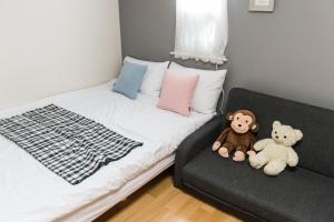two teddy bears sitting on a couch in a bedroom at The Blossom Yeonnam Guesthouse in Seoul