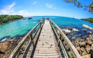 uma ponte de madeira sobre o oceano com pessoas sobre ele em APARTAMENTO 3 dormitorio VISTA PARA MAR em Bombinhas