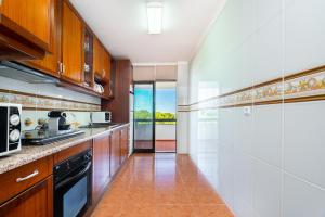 een keuken met houten kasten en een fornuis met oven bij WHome | Vilamoura Sunny Apartment in Quarteira