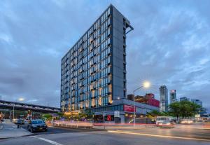 a tall building on a city street with cars at Z NYC Hotel in Queens