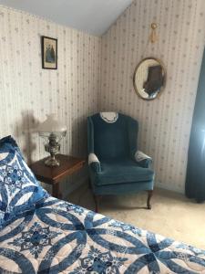 a bedroom with a blue chair and a mirror at B Street House Inn in Virginia City