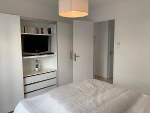 a white bedroom with a bed and a tv at L'Imperial in Le Grau-du-Roi