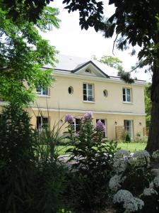 une grande maison blanche avec des fleurs violettes dans la cour dans l'établissement Les Buis de Boscherville Gite, à Hénouville