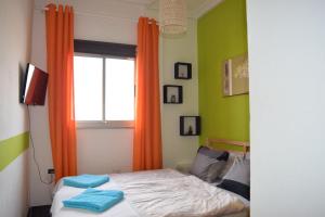 um quarto com uma cama e uma janela com cortinas laranja em B&B La Caleta Zimmer 1 (10 min. von El Medano) em La Mareta