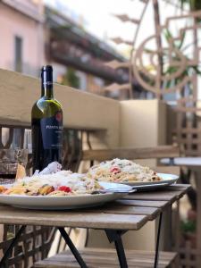 two plates of pizza on a table with a bottle of wine at Le BB in Bari