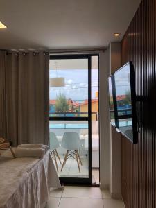 a bedroom with a bed and a view of a balcony at Laguna Beach Flat in Porto De Galinhas