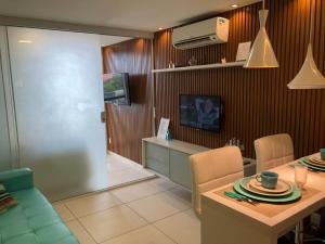 een woonkamer met een tafel en stoelen en een televisie bij Laguna Beach Flat in Porto De Galinhas