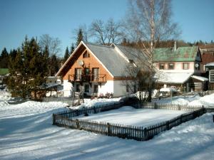 une maison avec une clôture dans la neige dans l'établissement Pension U Krtka - přímo u sjezdovky, à Harrachov