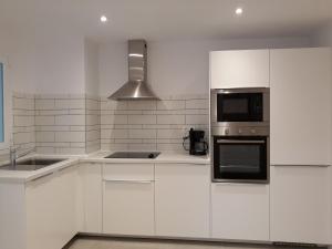a white kitchen with white cabinets and a microwave at Canovas by the Bull Ring in Málaga