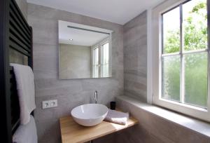 uma casa de banho com um lavatório branco e um espelho. em Zeeuws Huisje em Serooskerke