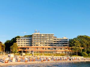 um grande edifício na praia com cadeiras em frente em Intermar Hotel & Apartments em Glücksburg