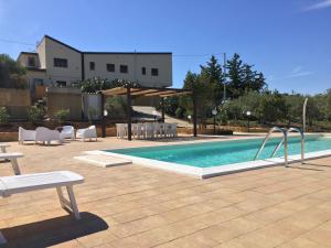 a swimming pool with chairs and a table and a building at Casale della Minaga in Agrigento