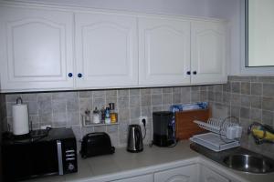 um balcão de cozinha com armários brancos e um micro-ondas em Vila Calaça em Funchal