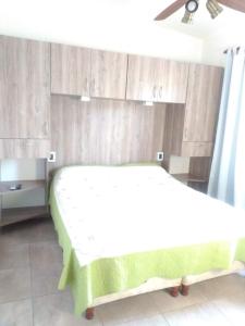 een slaapkamer met een wit bed en houten kasten bij Los Talas in Villa Carlos Paz