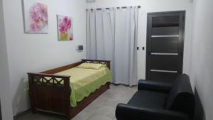 een kleine slaapkamer met een bed en een stoel bij Los Talas in Villa Carlos Paz