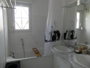 a white bathroom with two sinks and a window at Au gré du vent in Camiers