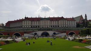 a large building with people sitting on the grass in front at Stadium Apart in Warsaw