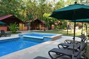 a swimming pool with two chairs and an umbrella at Cabañas Kin Balam Palenque in Palenque