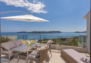 a table and chairs on a balcony with a view of the ocean at Apartmani D & J in Orasac