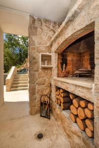 a large stone fireplace with a pile of logs at Apartmani D & J in Orasac