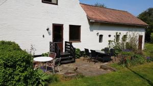 a white house with chairs and a table in front of it at Sænehus Husmandssted in Allinge