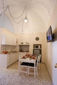 - une cuisine avec une table et des chaises blanches dans l'établissement CASA CAIROLI PUTIGNANO, à Putignano