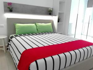 uma cama com um cobertor vermelho e almofadas verdes em Rogoredo Milan Apartments em Milão